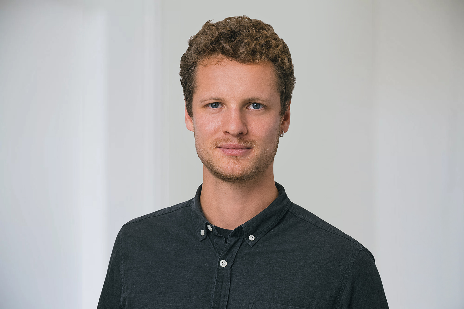 bag-relex_7697 2 Komprimiert ein Mann mit kurzen Haaren blickt in die Kamera. Er trägt ein dunkles Hemd.